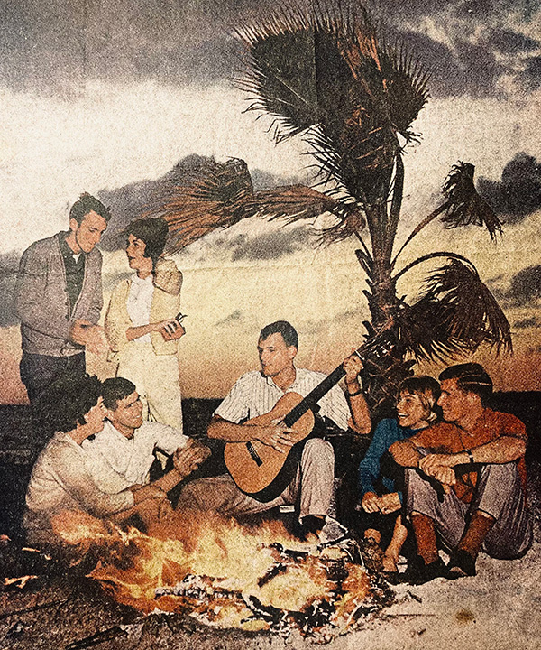 Eckerd students around a bonfire on beach with guitar in 1963