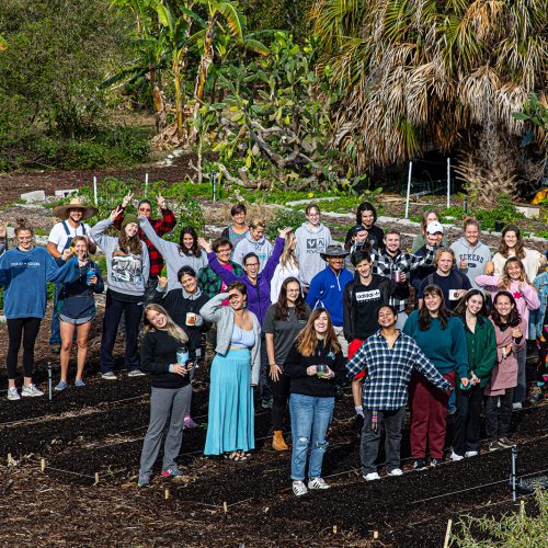 Class of twenty students and professors in a group standing in garden
