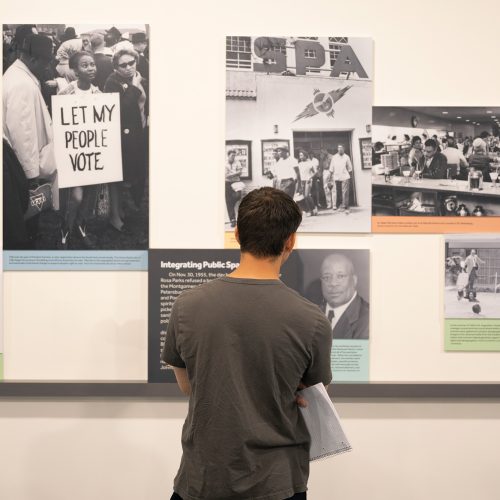 Student looks at a wall of historical images