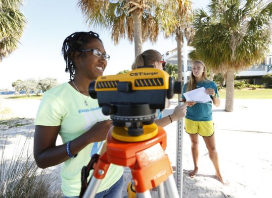 Three female students survey on South Beach with Geoscience and Marine Science Professor Laura Wetzel.