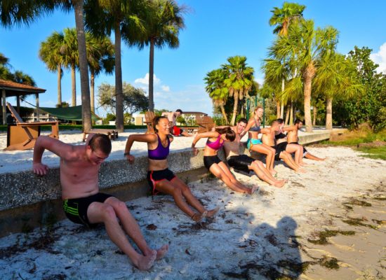 Students do crunches against sea wall for Xfit club on South Beach