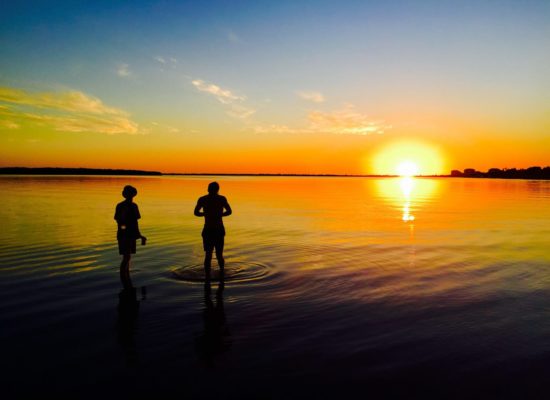 Two students standing in bay while the sun sets
